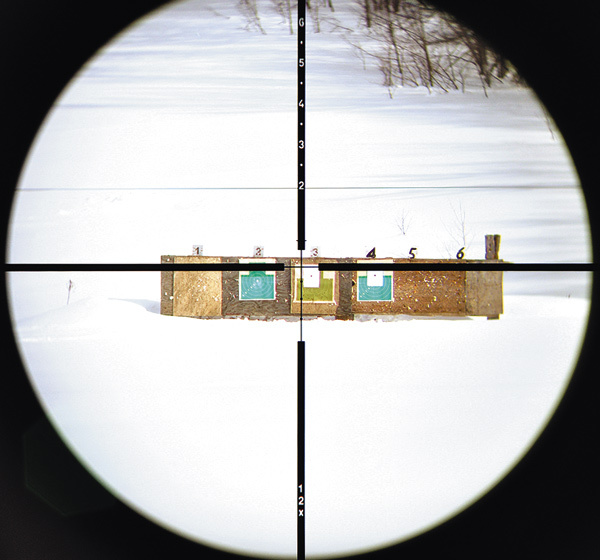 Изображение ОПТИЧЕСКИЙ ДАЛЬНОМЕР. 
Для определения дистанции нужно поместить объект между центром перекрестия и соответствующей отметкой на верхней перекладине креста. Выкручиваем кратность так, чтобы объект занял все пространство между отметками. Как только мы добьемся этого, посмотрим на передвигающуюся по вертикали тонкую горизонтальную линию в верхней части сетки. Она должна остановиться напротив одной из цифр, обозначающих дистанцию в сотнях ярдов.
Итак, нам известно расстояние до цели, и теперь можно просто ввести нужную вертикальную поправку барабаном прицела и стрелять по центру перекрестия. А можно воспользоваться нижней частью сетки и прицеливаться по одной из размеченных точек компенсации понижения траектории пули на нижней перекладине — конкретно по той точке, которая соответствует полученной при измерении дистанции, соответственно 300, 400, 500 или 600 ярдов.
Конечно, возникает вопрос по баллистике. Ведь разные боеприпасы имеют разную траекторию полета пули. Поэтому совместимость калибров с сеткой нужно проверять экспериментально.