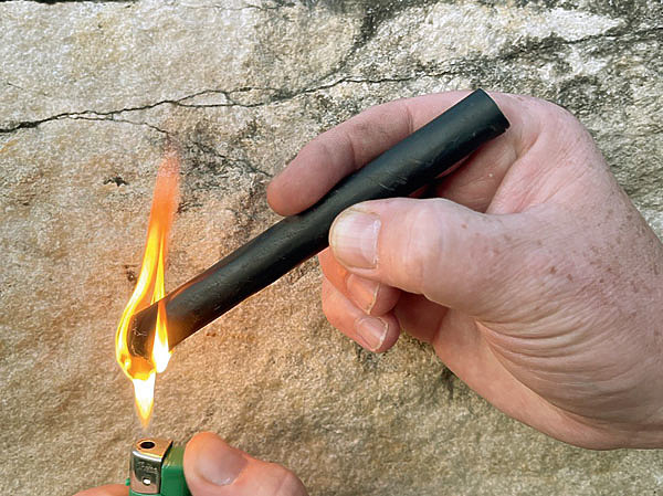 Изображение ТРУБКА ДЛЯ РОЗЖИГА. Небольшой отрезок метровой резиновой трубки диаметром один сантиметр, которую обычно используют как кровеостанавливающий жгут, — это отличное средство для розжига огня. Если держать такой отрезок под углом более 45° и поджигать его нижний конец пламенем спички или зажигалки, то внутри трубки образуется тяга, которую можно регулировать изменением угла наклона. Загоревшейся трубкой удобно разжигать пламя печки или костра. Оставшуюся после розжига часть можно потушить, воткнув ее в грунт, снег или погрузив в воду, чтобы приберечь до следующего раза. Фото автора. 