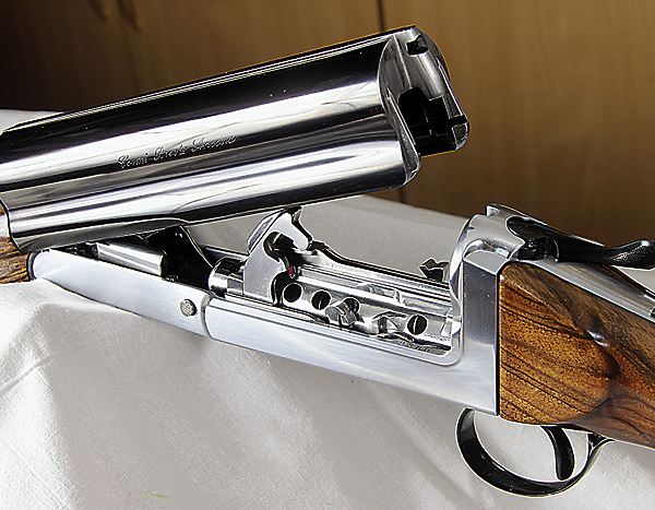 Изображение Beretta не одинока
Единственным аналогом модели Beretta UGB25, да и то очень приблизительным, можно считать ружье итальянской компании Cosmi. Хотя по большому счету, похожи они только тем, что это полуавтоматические ружья с откидным стволом. В остальном их конструкции совершенно различны. Cosmi имеет восьмизарядный магазин, что делает его пригодным не только для стендовой стрельбы, но и для охоты. Cosmi работает на длинном ходе ствола, и, как следствие, затворная коробка (да и сам затвор) откидывается вместе со стволом. У Beretta откидывается только ствол, что выглядит более элегантно. Надо отметить, что среди полуавтоматов в последнее время стала популярна схема работы с коротким ходом ствола. Считается, что при использовании этой схемы перезаряжание происходит быстрее. Интересно также, что конструкторы Beretta смогли максимально опустить ствол, тем самым уменьшив его подброс после выстрела. Рычаг отпирания на Cosmi традиционный, расположен на верхней части коробки, а у Beretta UGB25 он слева и сильно выступает. На мой взгляд, вариант Cosmi все же более интересен.